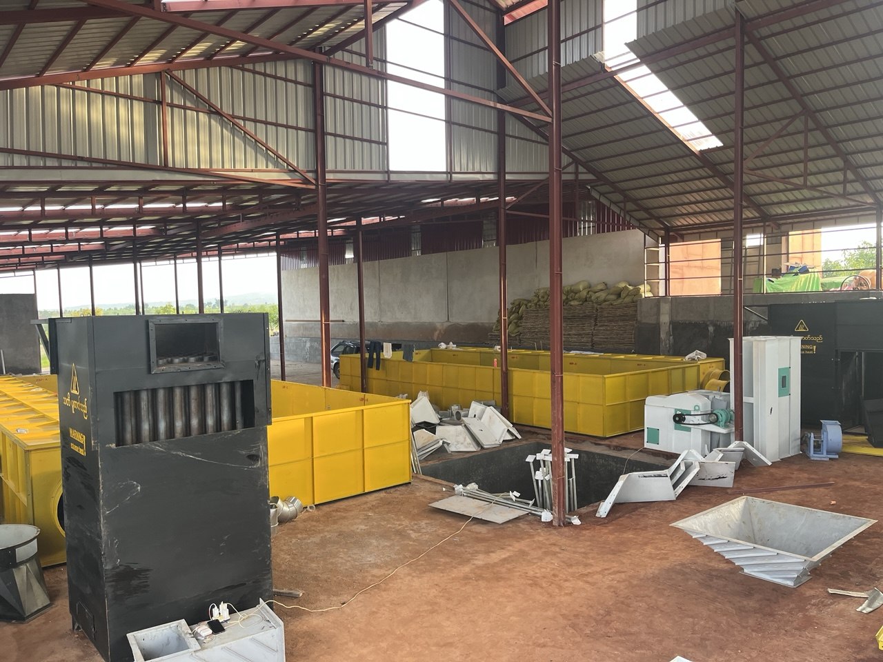 BPE agricultural machinery during site installation, with yellow drying beds inside a steel-roofed building